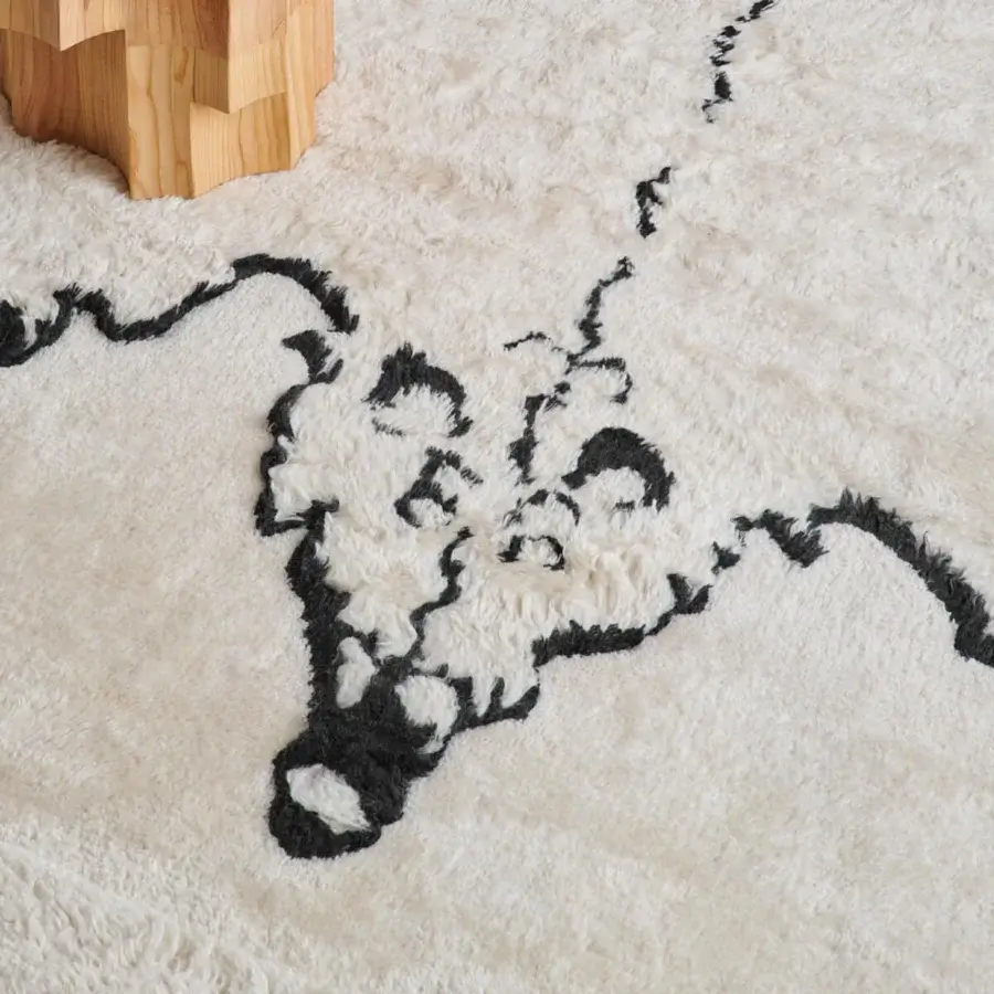 Captivating Amini Tapiorso rug hand-knotted in India with ivory wool exhibiting a bold black bear motif and meticulous carving