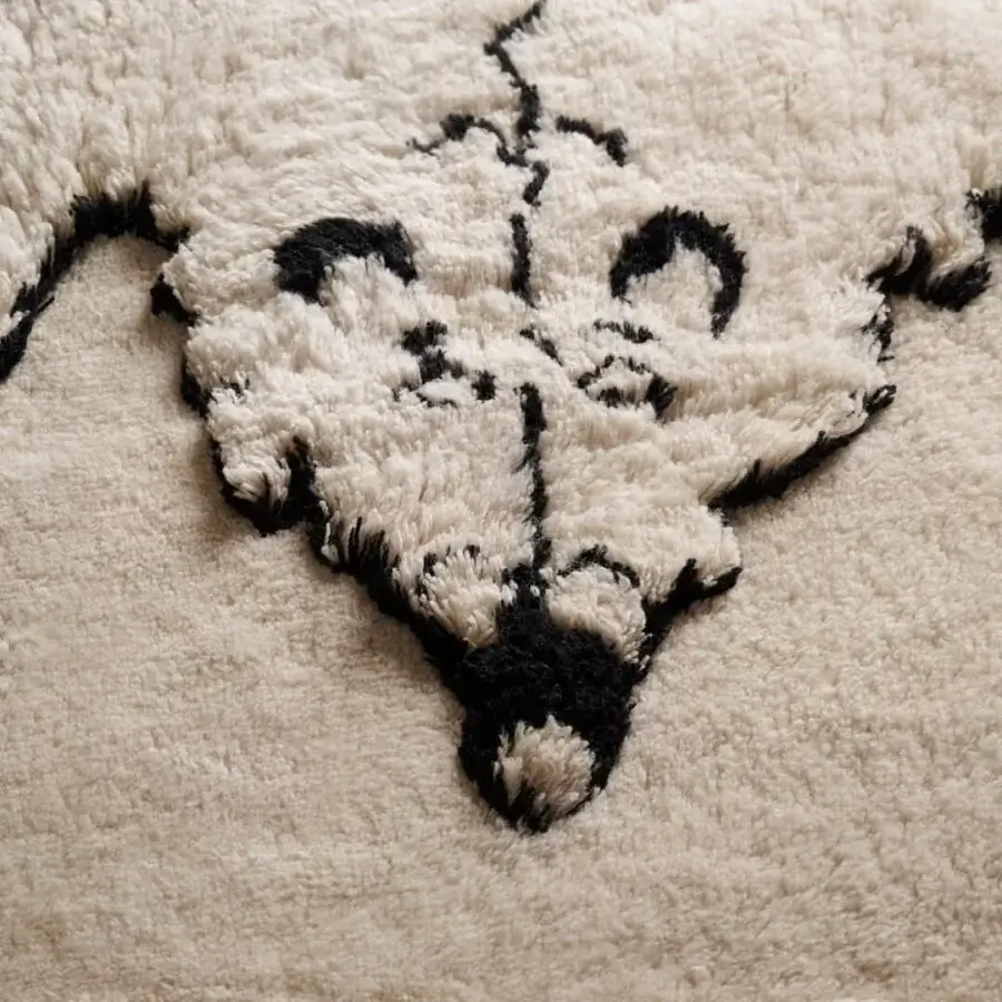 Distinguished Amini Tapiorso rug hand-knotted in India with ivory wool displaying a graphic black bear motif and carved texture
