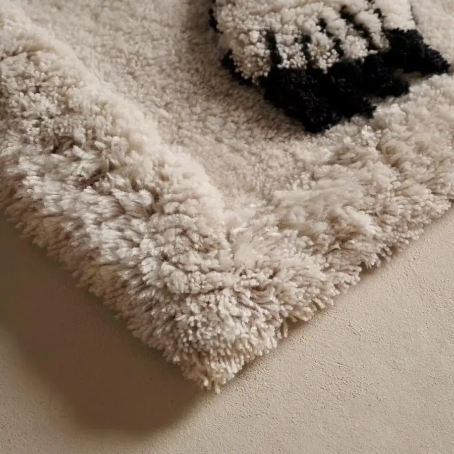 Superior Amini Tapiorso rug hand-knotted in India with ivory wool displaying a dark brown bear face pattern and clipped carving