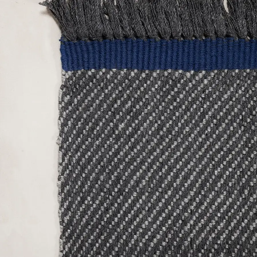 Superior Amini Sesame rug hand-woven in dark gray recycled PET with a vibrant blue band and hand-clipped finish