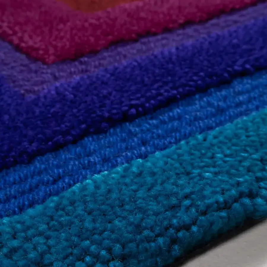 Lavish Amini Domino rug hand-tufted from New Zealand wool with gradient bands in turquoise, purple, red, and orange with a carved texture