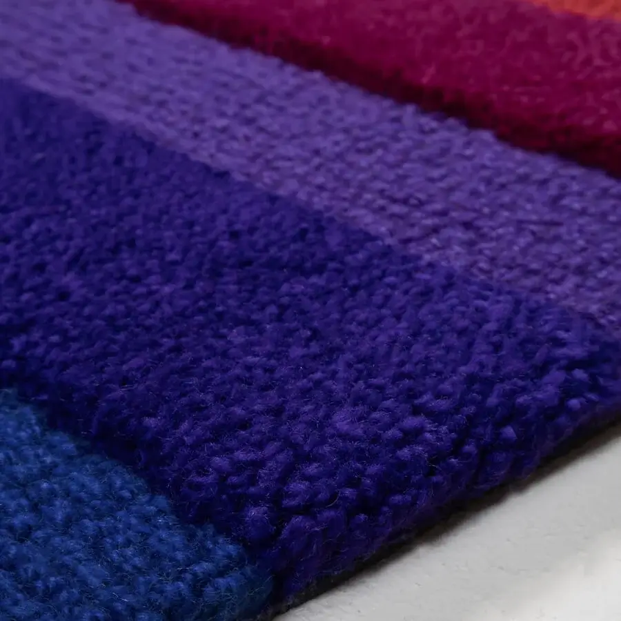 Lavish Amini Domino rug handcrafted with purple and orange New Zealand wool exhibiting a clipped carved texture