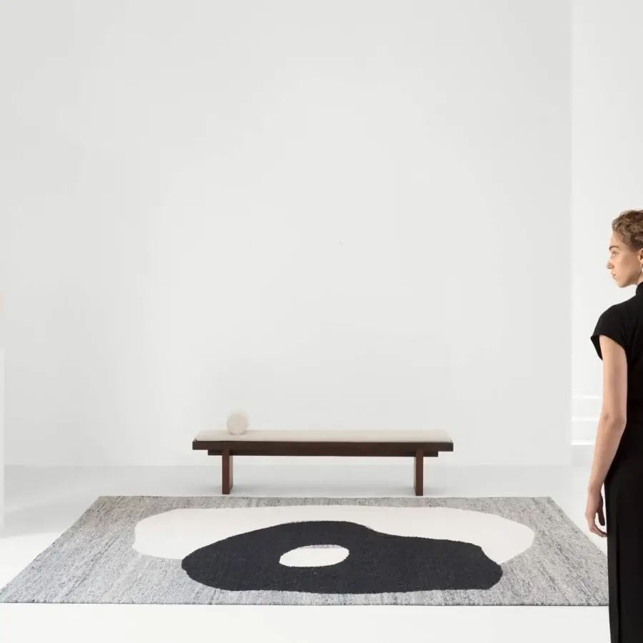 Lavish Amini Jean rug displaying a hand-clipped asymmetrical design woven with 100% wool in shades of ivory, dark grey, and brown