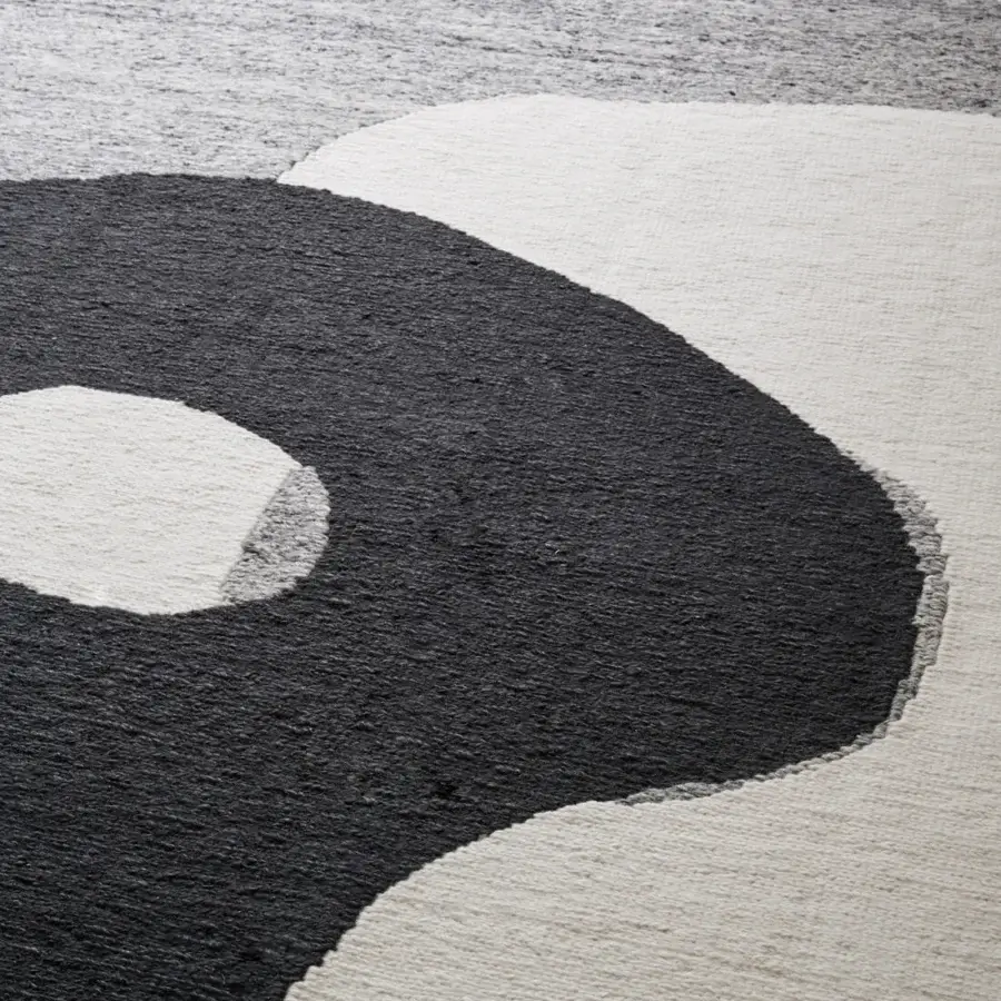 Distinguished Amini Jean rug displaying a balanced Yin and Yang symbol hand-clipped with soft wool in dark grey and ivory tones