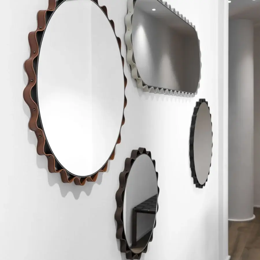 Exceptional Enrico Pellizzoni Glimt mirror built with a round, wavy frame in reddish-brown leather and bright brass studs