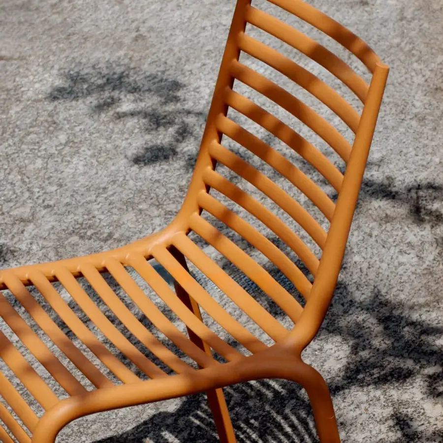 Superior Driade Pip-e chair molded in warm orange polypropylene with seamless horizontal slats across seat, backrest and legs