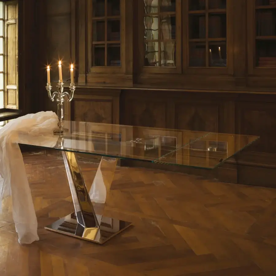 Superior Naos Minosse table with a glass top and sculptural v-shaped base in a bright silvery metal finish
