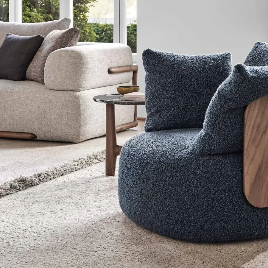 Distinguished Porada Calin armchair built with curved Canaletto walnut and enveloping deep navy bouclé upholstery with a swivel metal base
