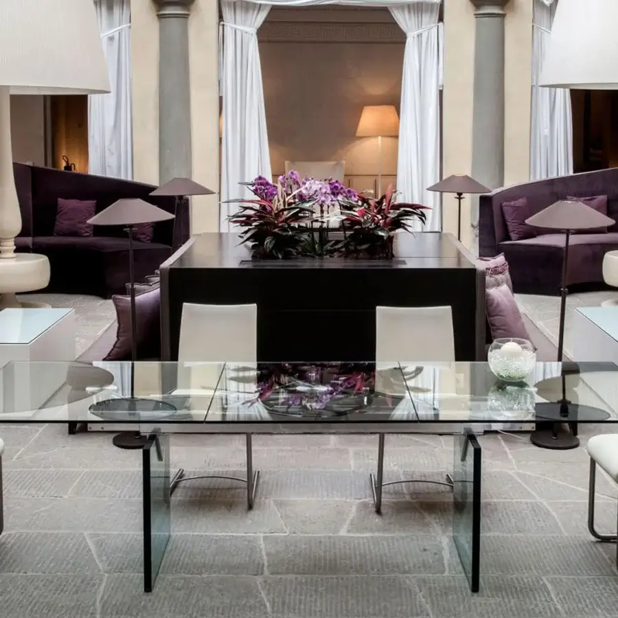 Elegant Naos Quasar table built with a synchronized extension mechanism, stratified glass legs and dark-toned metal base