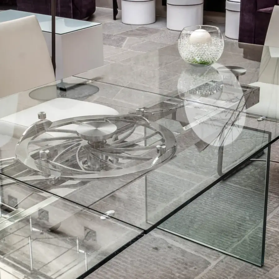 Distinguished Naos Quasar table crafted with a clear glass top and stratified glass legs, showcasing a sculptural silver-toned element beneath a glossy surface