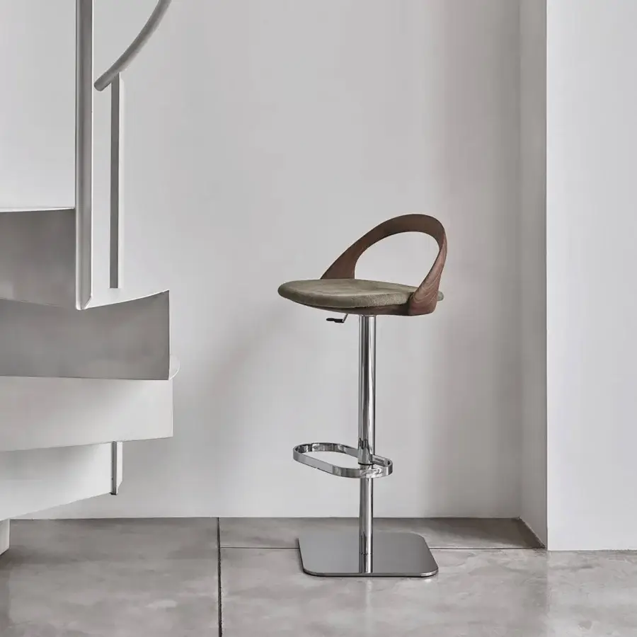Distinguished Porada Ester stool with gentle curves, a muted olive green textile seat, and polished silver-toned metal support crafted in wood with a natural finish