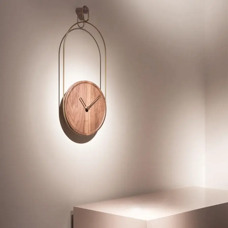 Distinguished Nomon Eslabón Wall Clock with a natural walnut plate gently supported by curved gold-toned metal and a satin finish