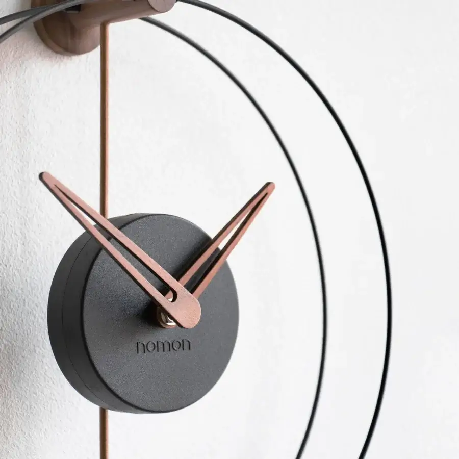 Superior Nomon Nano wall clock with a dark gray face, light gray metal rings and a satin medium-toned wood bracket