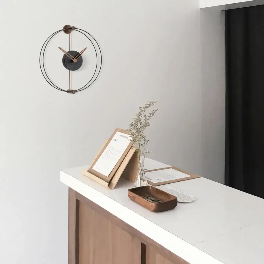 Elegant Nomon Nano wall clock in walnut wood with contrasting black and white tones and a dark matte finish