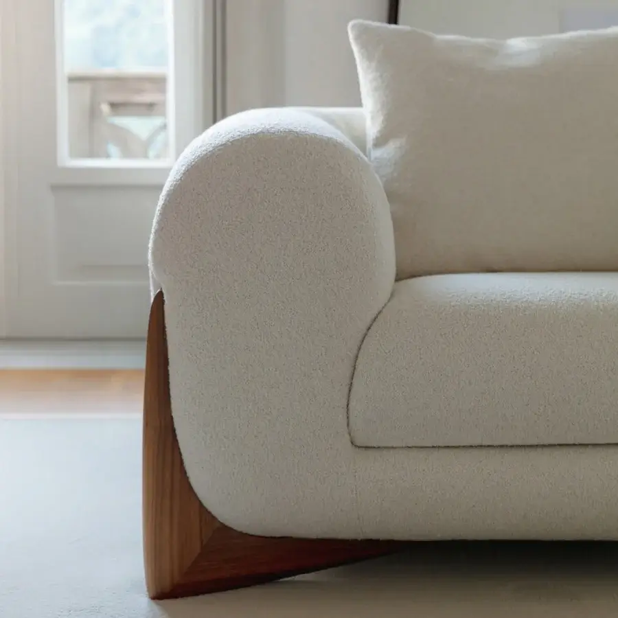 Superior Porada Softbay sofa with rounded silhouette and cotton, linen, wool bouclage upholstery in creamy off-white with satin Canaletta walnut end-feet