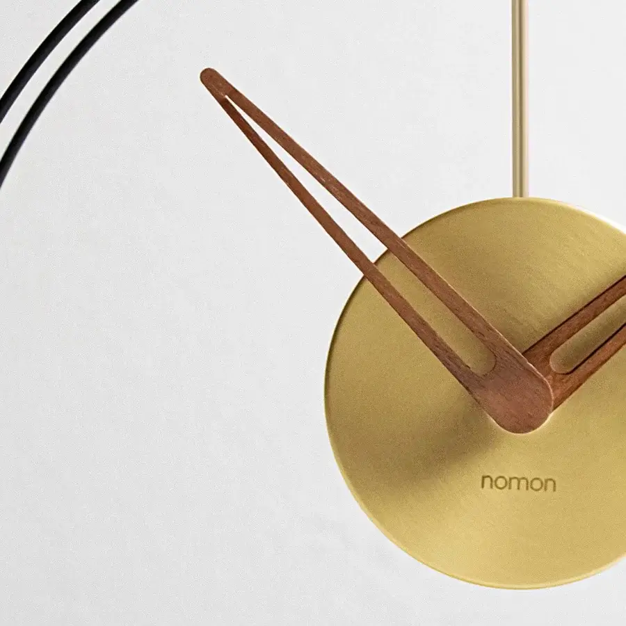 Elegant Nomon Mini Aire table clock with a golden metallic face, walnut hands and double black fiberglass rings
