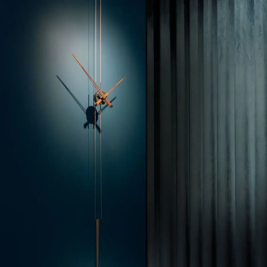 Captivating Nomon Péndulo Pendulum Clock timepiece with a brushed metal finish and slender hands in subtle bronze tones