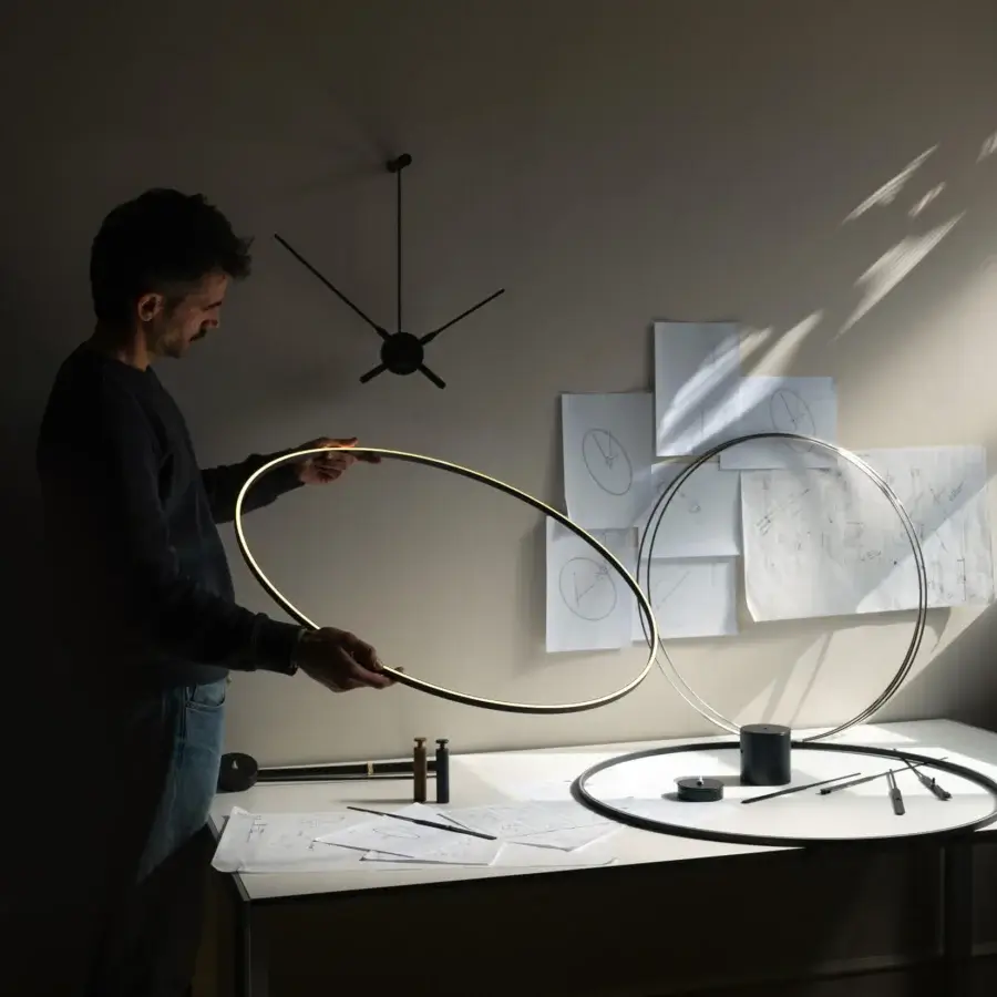 Distinguished Nomon Ombra clock lamp crafted in black anodized aluminum with a warm golden glow and refined finish