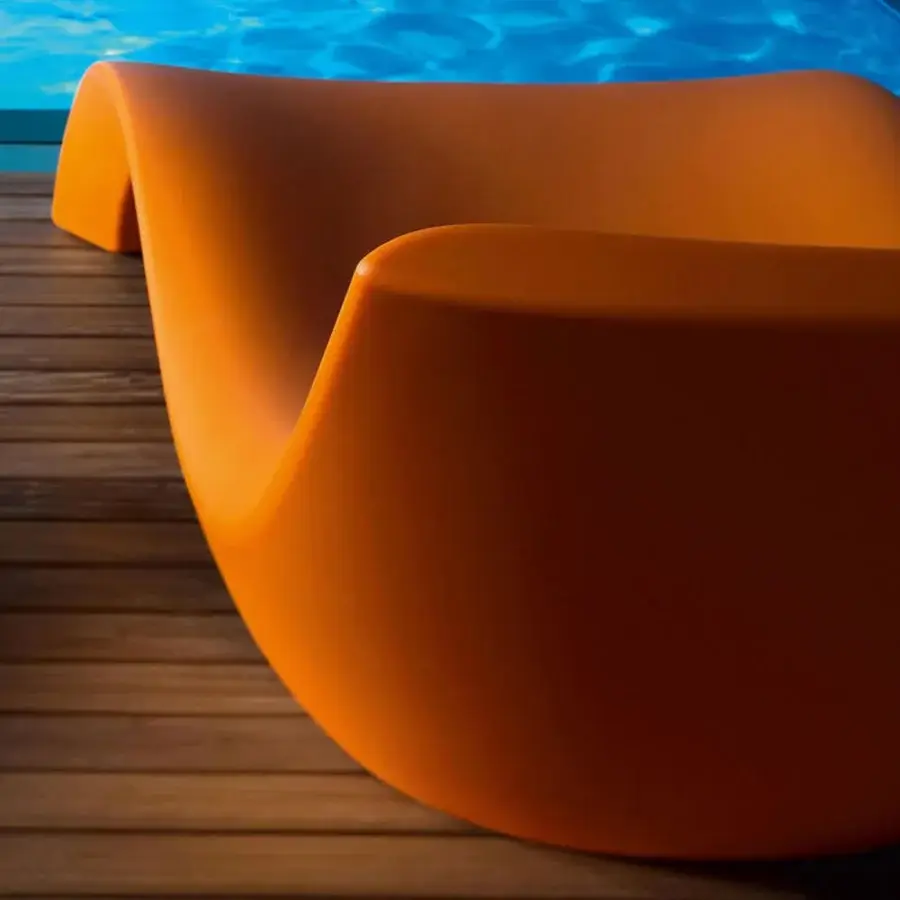 Distinguished MY YOUR Cloe lounger with organically curved form crafted in vibrant orange Poleasy® material and glossy finish