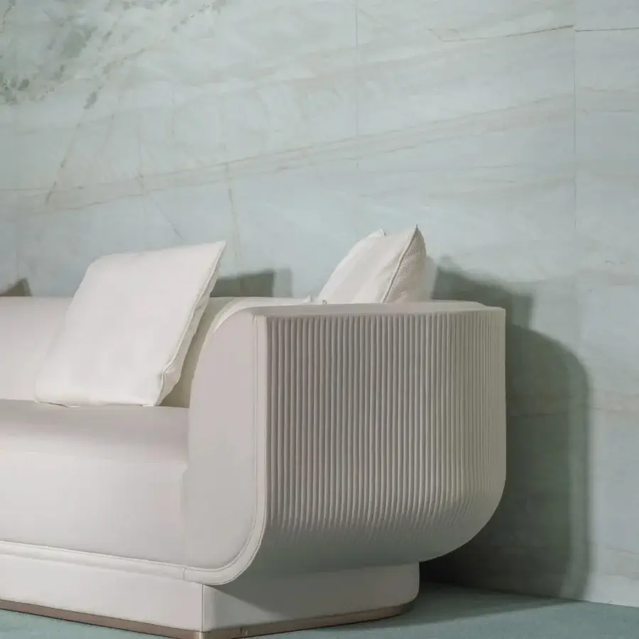 Distinguished Visionnaire Foster sofa with a wide silhouette and cream-toned fabric exhibiting vertical canneté quilting with a rose-gold plinth base