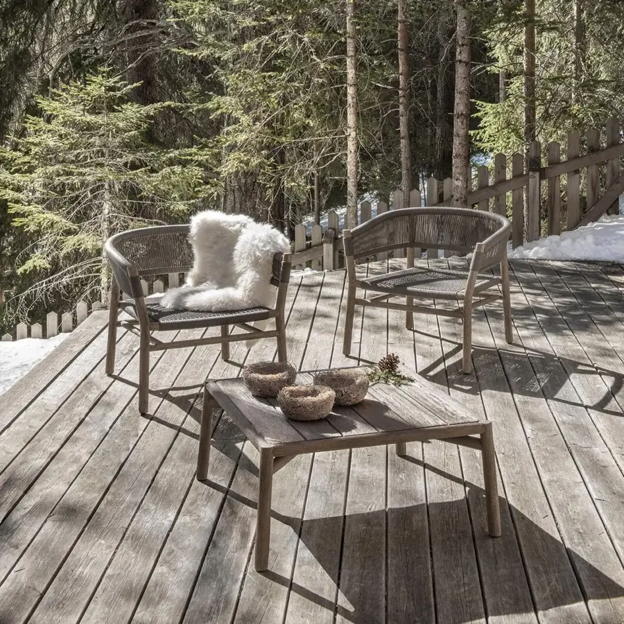 Elegant Ethimo Kilt lounge chair with natural fibre weave and gently curved teak construction