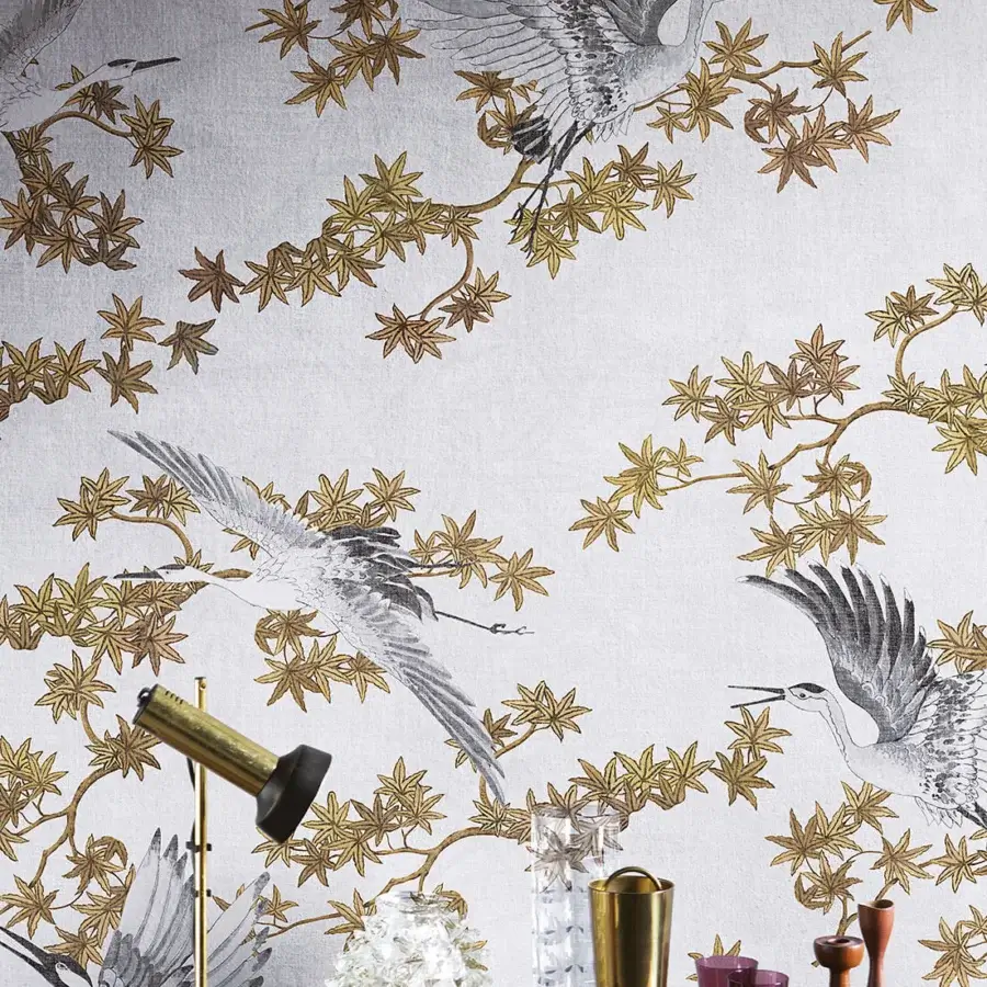Exclusive LondonArt Sya wallpaper presents stylized cranes and foliage in grey and metallic gold with a matte non-woven finish