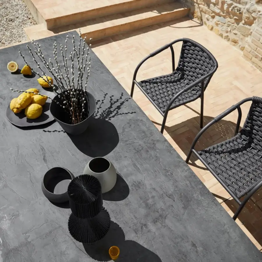 Captivating Roberti Rattan Lipari table with a dark charcoal HPL tabletop and 304 stainless steel base exhibiting a subtly textured finish