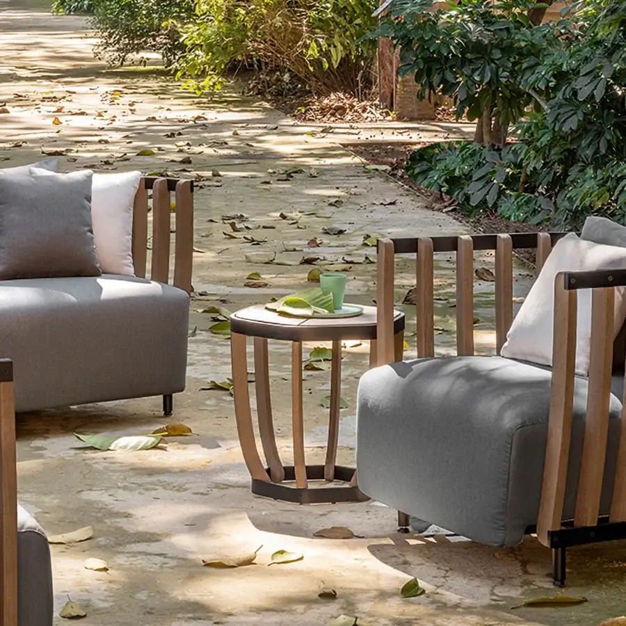 Elegant Ethimo Swing side table with dark matte metal base and cylindrical teak slats with a smooth satin finish