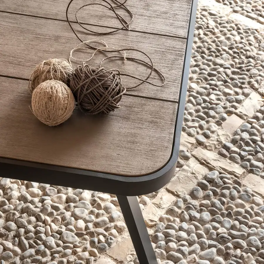 Harmonious Ethimo Swing table crafted in dark grey aluminum with a textured grey-brown teak slat tabletop