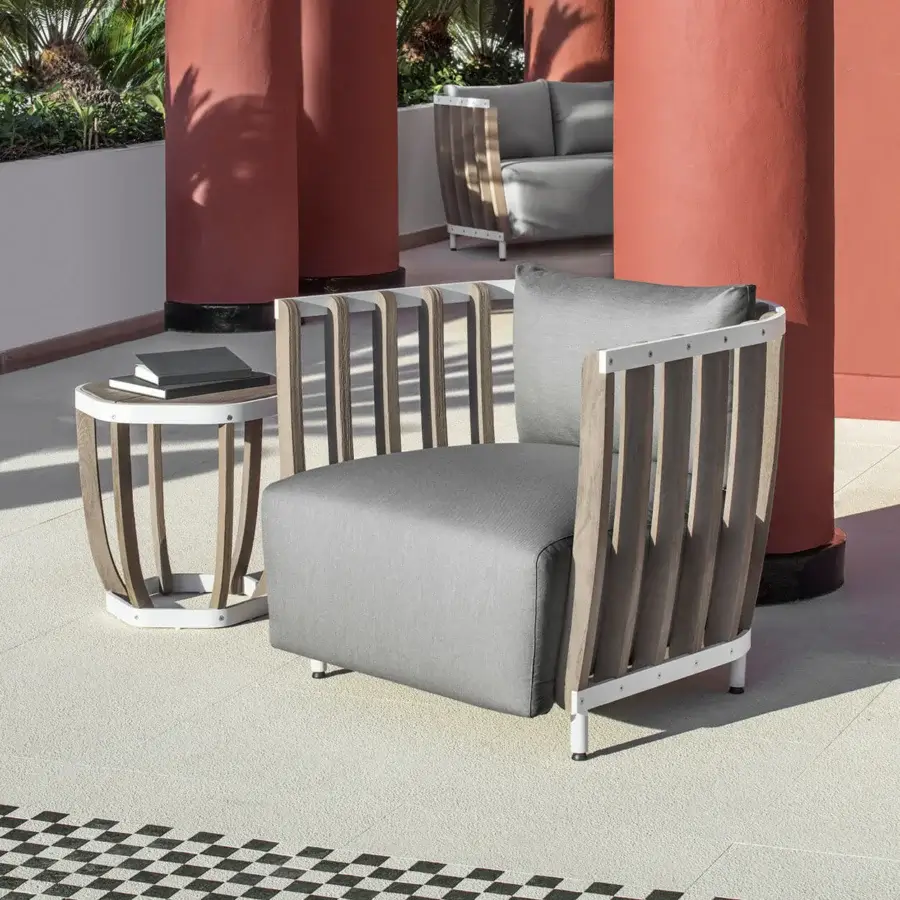 Refined Ethimo Swing lounge chair with white matte metal, warm teak slats and comfortable gray cushion