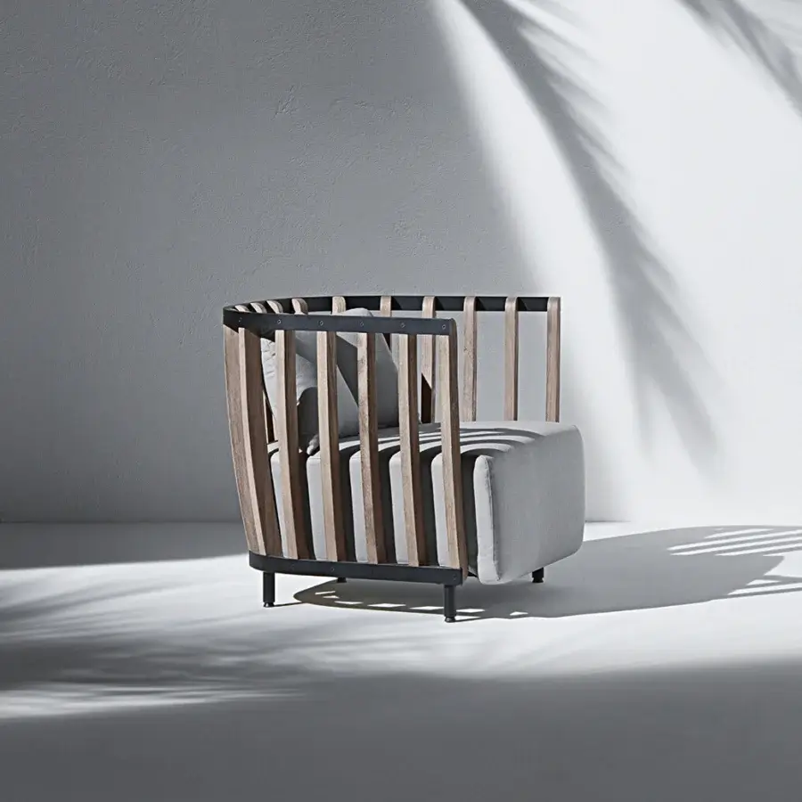 Refined Ethimo Swing lounge chair with a sleek metal frame, warm teak slats and light gray textile cushion