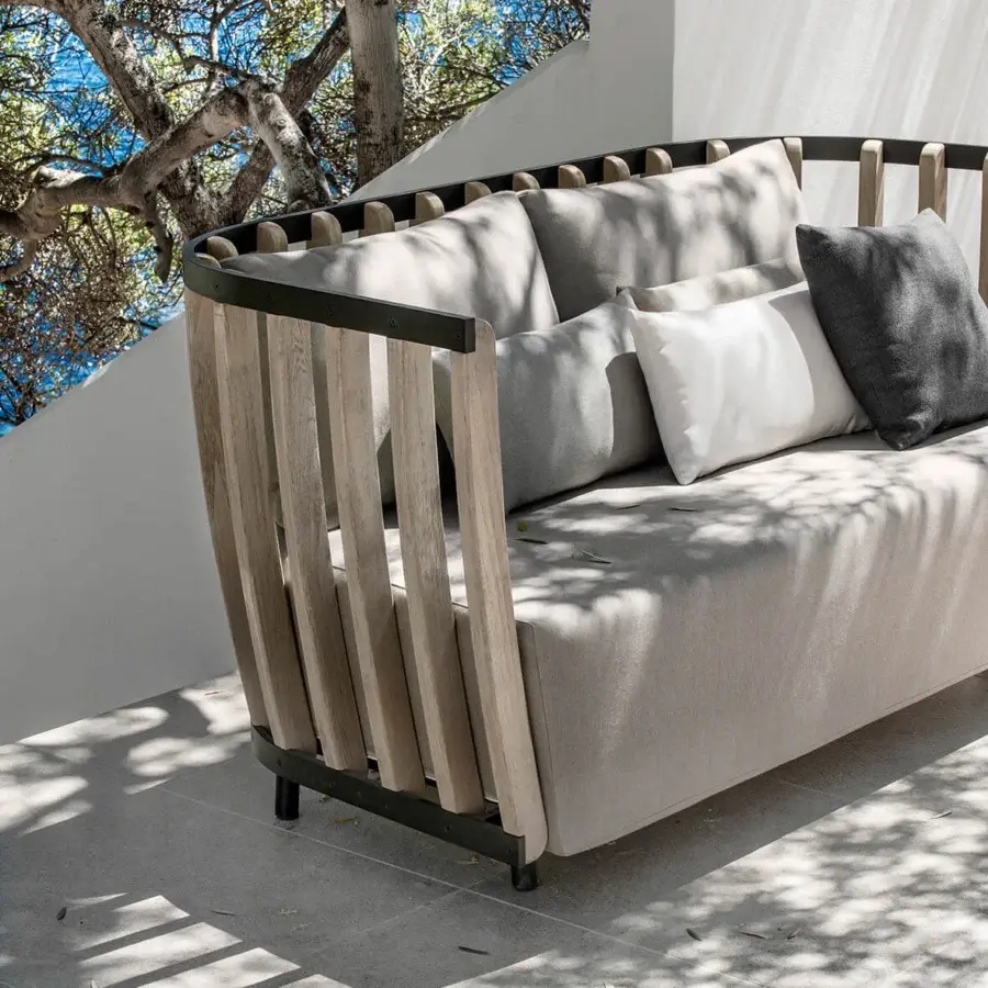 Architectural Ethimo Swing sofa crafted with dark-toned metal, lightly textured teak wood, and neutral beige cushions for inviting outdoor lounging