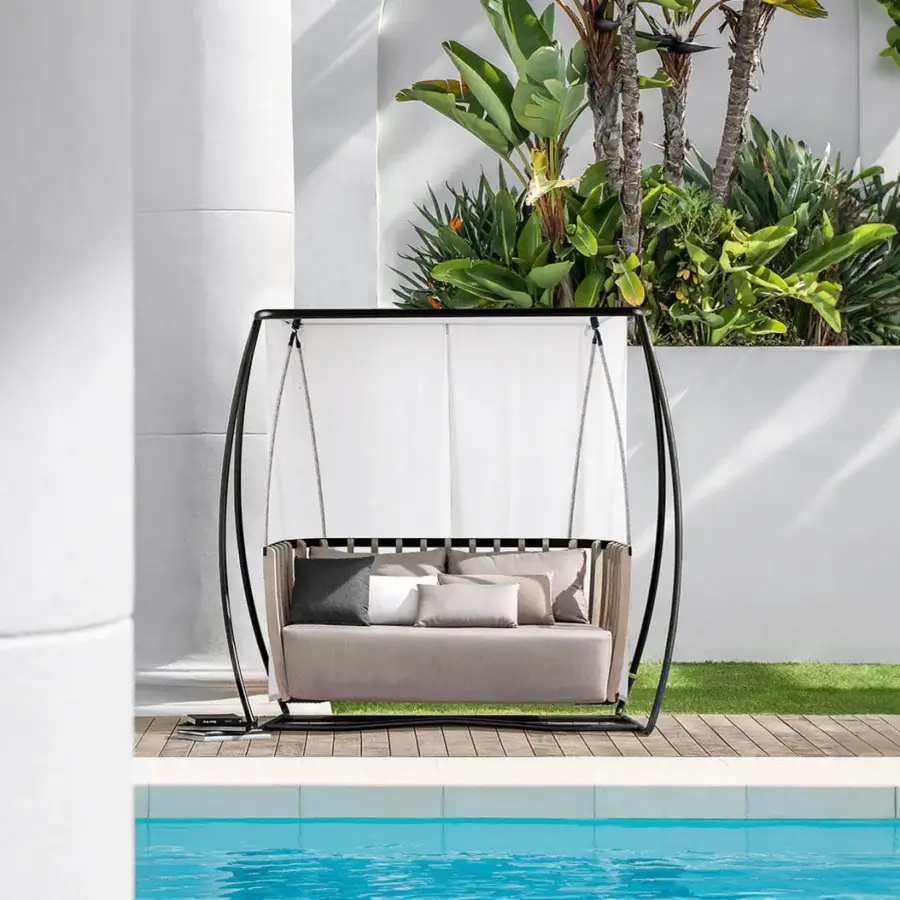 Distinctive Ethimo Swing hanging sofa crafted with a slender metal frame, teak slats, light gray textile upholstery, and sheltering white fabric canopy