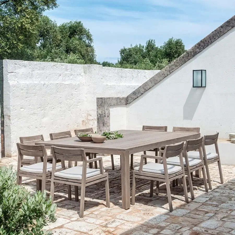 Captivating Ethimo Costes armchair with FSC-certified teak frame and comfortable light-colored cushions in a warm natural finish