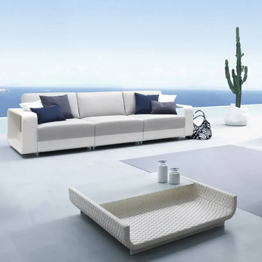 Superior Roberti Rattan Hamptons sofa with aluminum frame, woven Sunweave finish, and navy blue accent cushions in light cream