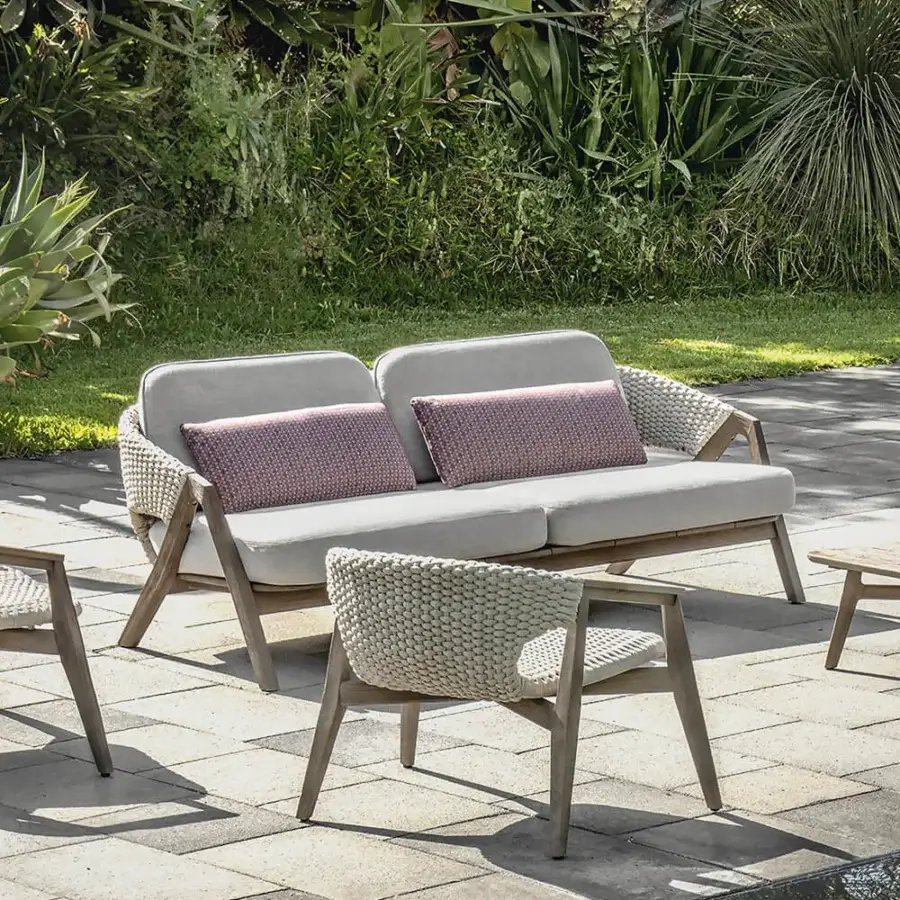 Sophisticated Ethimo Knit sofa with sinuous teak frame, light beige knit textile upholstery and reddish-pink geometric cushions