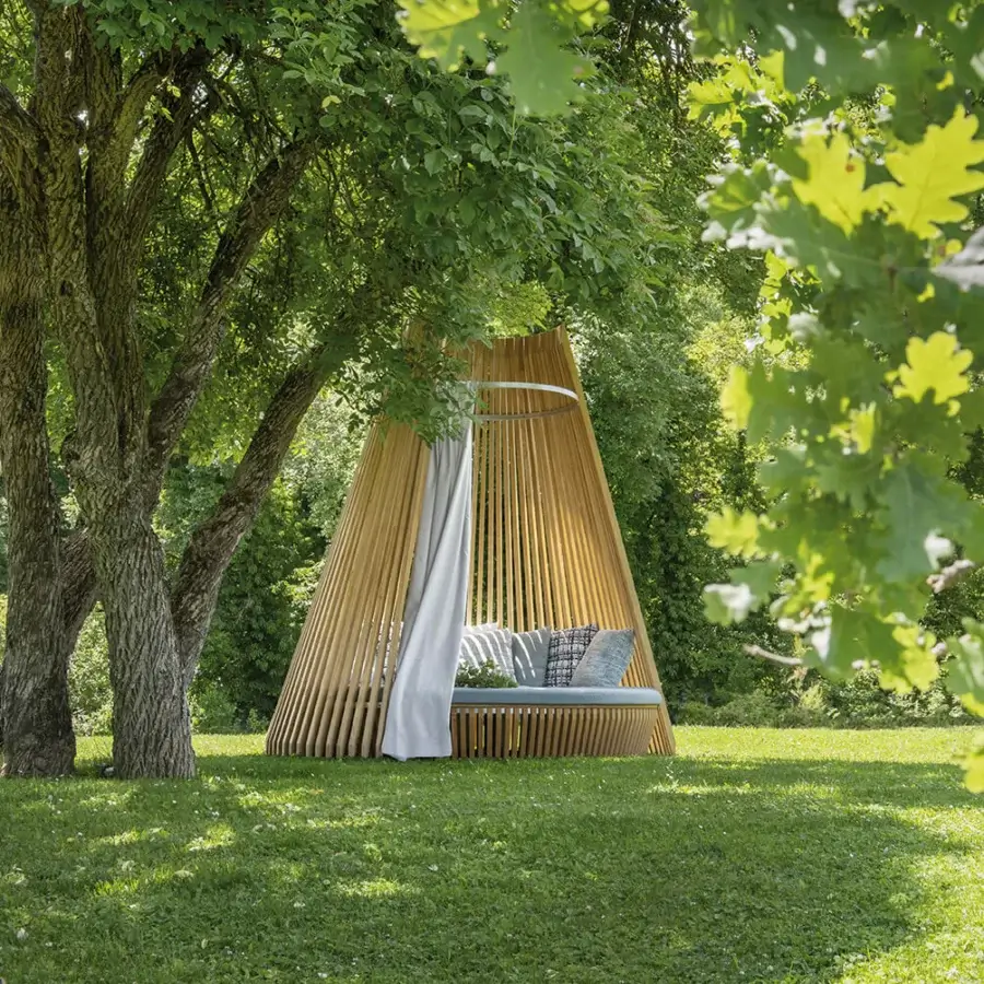 Elegant Ethimo Hut daybed crafted in warm-toned wood with a light-colored textile canopy within a conical silhouette