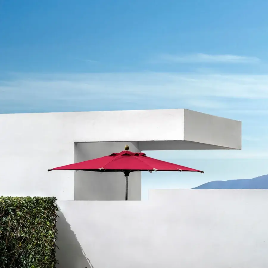 Lavish Ethimo Free Umbrella parasol in red textile with a dark metal pole and golden finial
