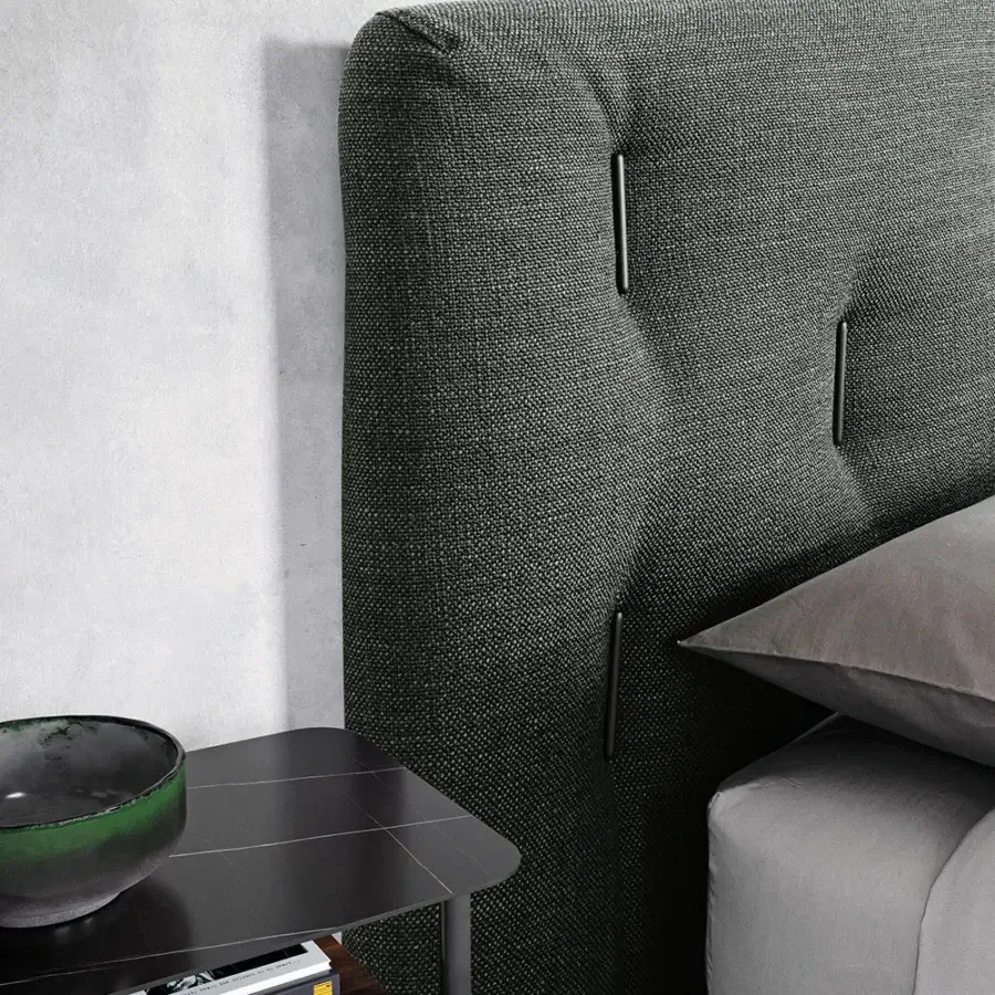 Superior Dallagnese Bars bed with a tall vertically-lined headboard upholstered in muted gray fabric and warm brown wood cabinetry