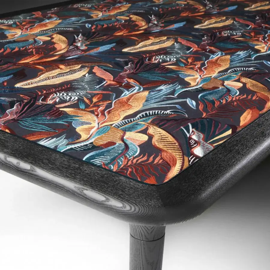 Exclusive Black Tie Caius table crafted in Italy with a textile surface displaying foliage in blues, oranges, and reds with a dark matte wood frame