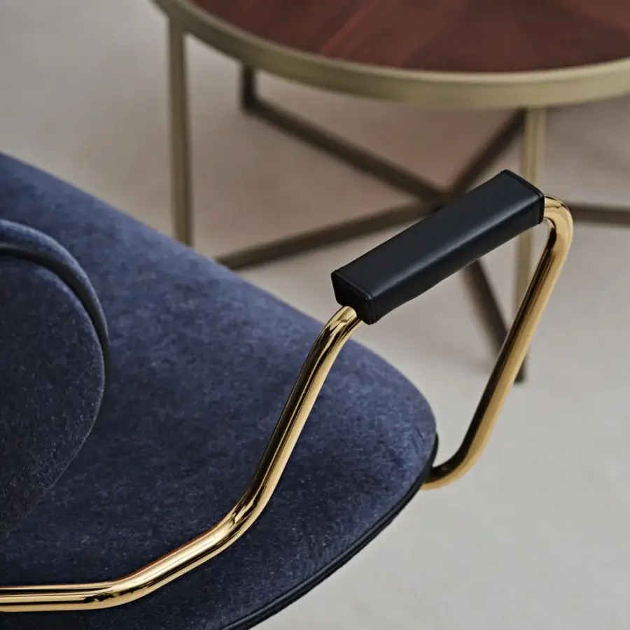 Distinguished Black Tie Asia swivel lounge chair upholstered in deep blue textured textile with a polished gold metal frame and sleek black capped armrests