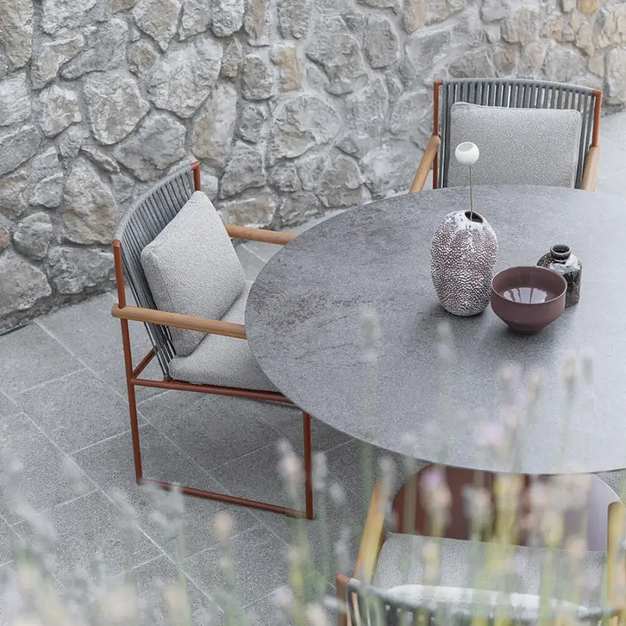 Distinguished Atmosphera Arena round table with medium gray gres and bronze-toned metal pedestal in a subtly textured matte finish