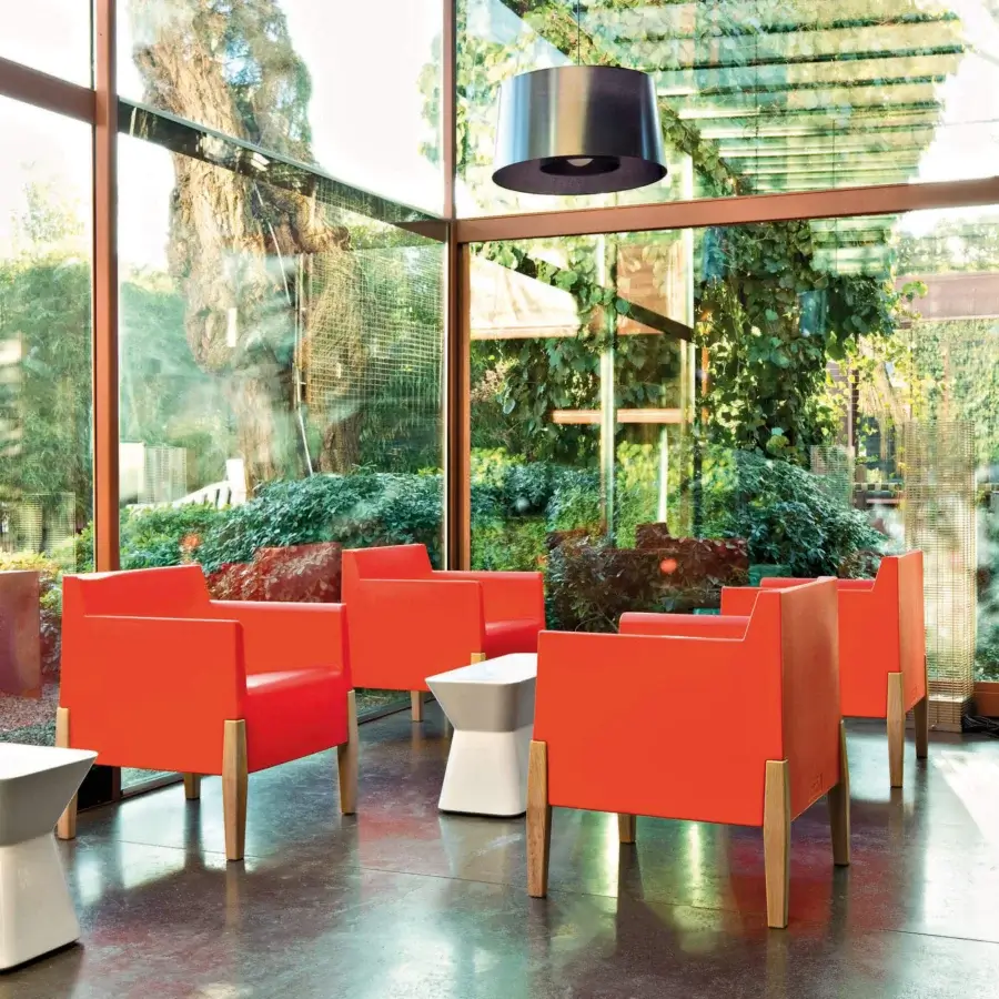 Distinctive Serralunga Kubrick lounge chair with vibrant orange LLDPE and warm Iroko wood legs in a matte finish