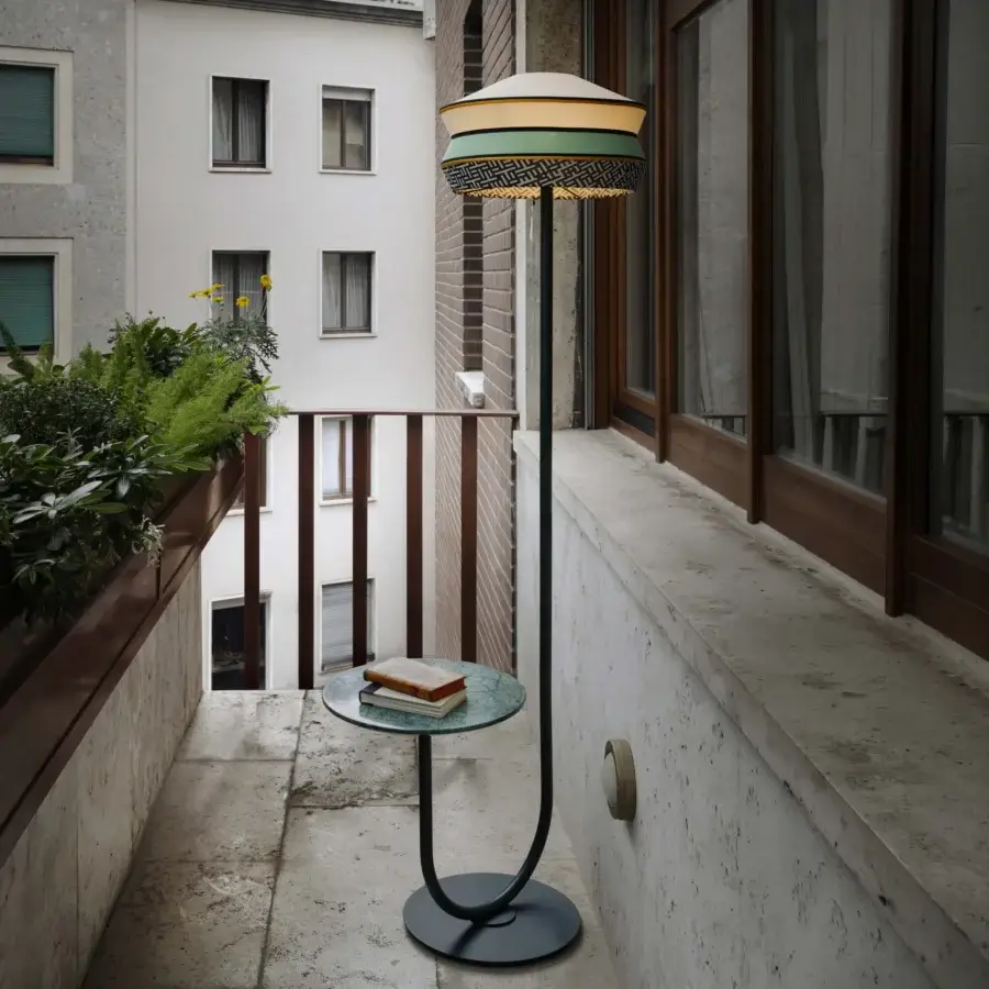Distinguished Contardi Calypso Outdoor Floor Lamp with dark gray metal stem and multi-material lampshade in pale yellow, teal, white, and orange crafted with a marble side table