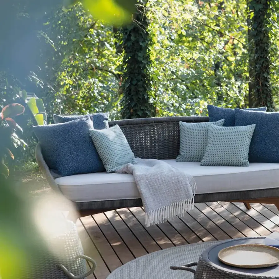Distinctive Atmosphera Ludo sofa with organic shape crafted in teak wood and woven synthetic material with muted blue cushions