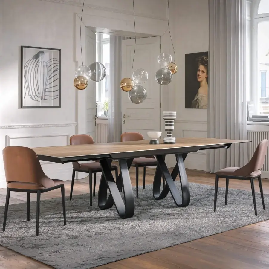 Superior Tonin Casa Butterfly Ext table built in medium-brown travertino with a dramatically sculpted dark-colored metal base