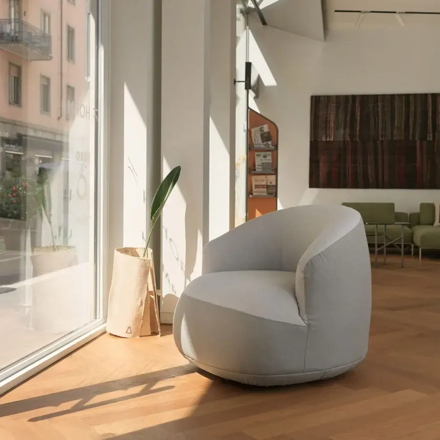 Exceptional Horm Edith swivel lounge chair with enveloping form upholstered in subtly textured dusty blue-grey textile and curved lines