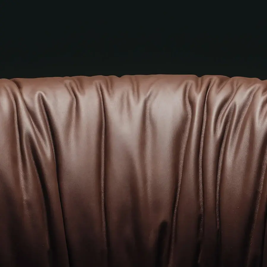 Premium Visionnaire Hampshire Lounge Chair in chocolate‑brown leather with sheen and pleated backrest against black backdrop