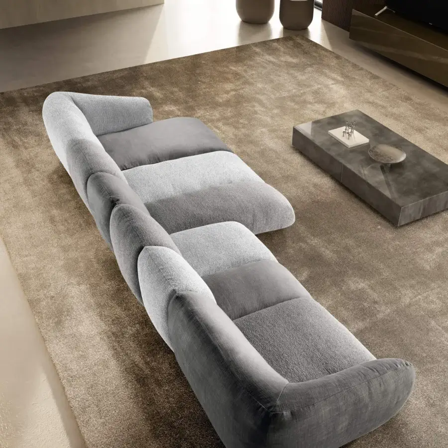 Elegant sectional with matte textile upholstery, rounded cushions, tiered dark and light grey palette, low‑profile silhouette, lines