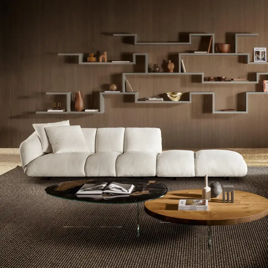 Elegant sectional with textured nubby off‑white finish, soft curved lines, armless deep seating, seamless lounge extension, dark feet on brown rug